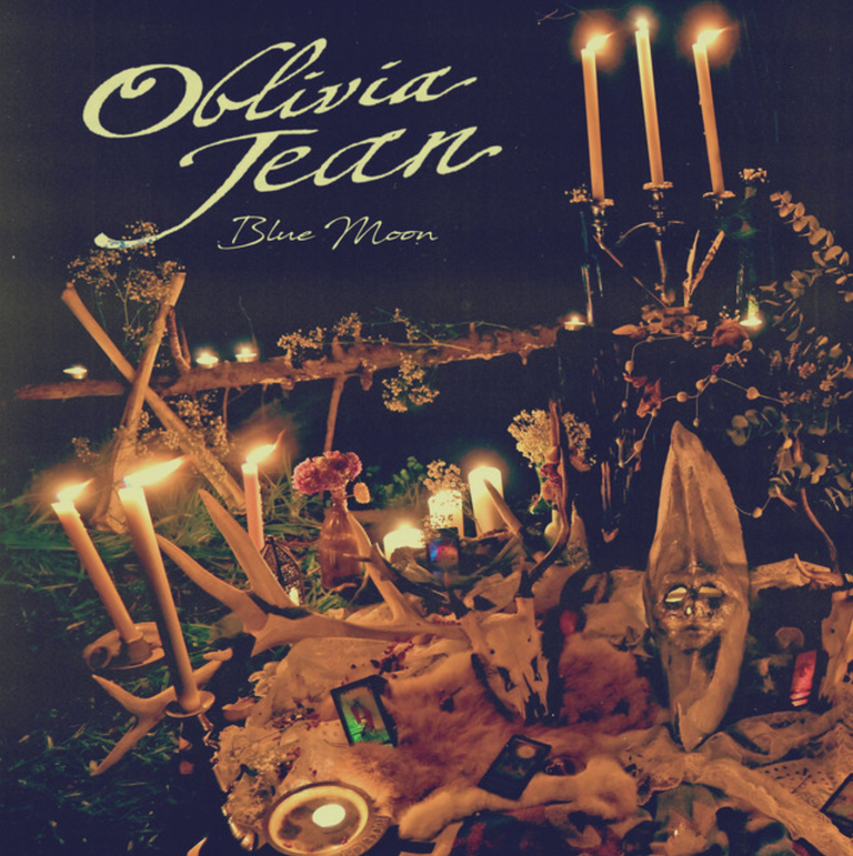 Single artwork for Oblivia Jean's Blue Moon featuring a glowing altar with lit candles, animal skull, antlers, and tarot cards at night.